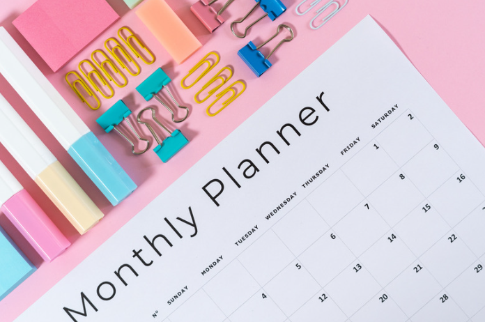 A pink desk top displayed a monthly calendar pad and organized office supplies.