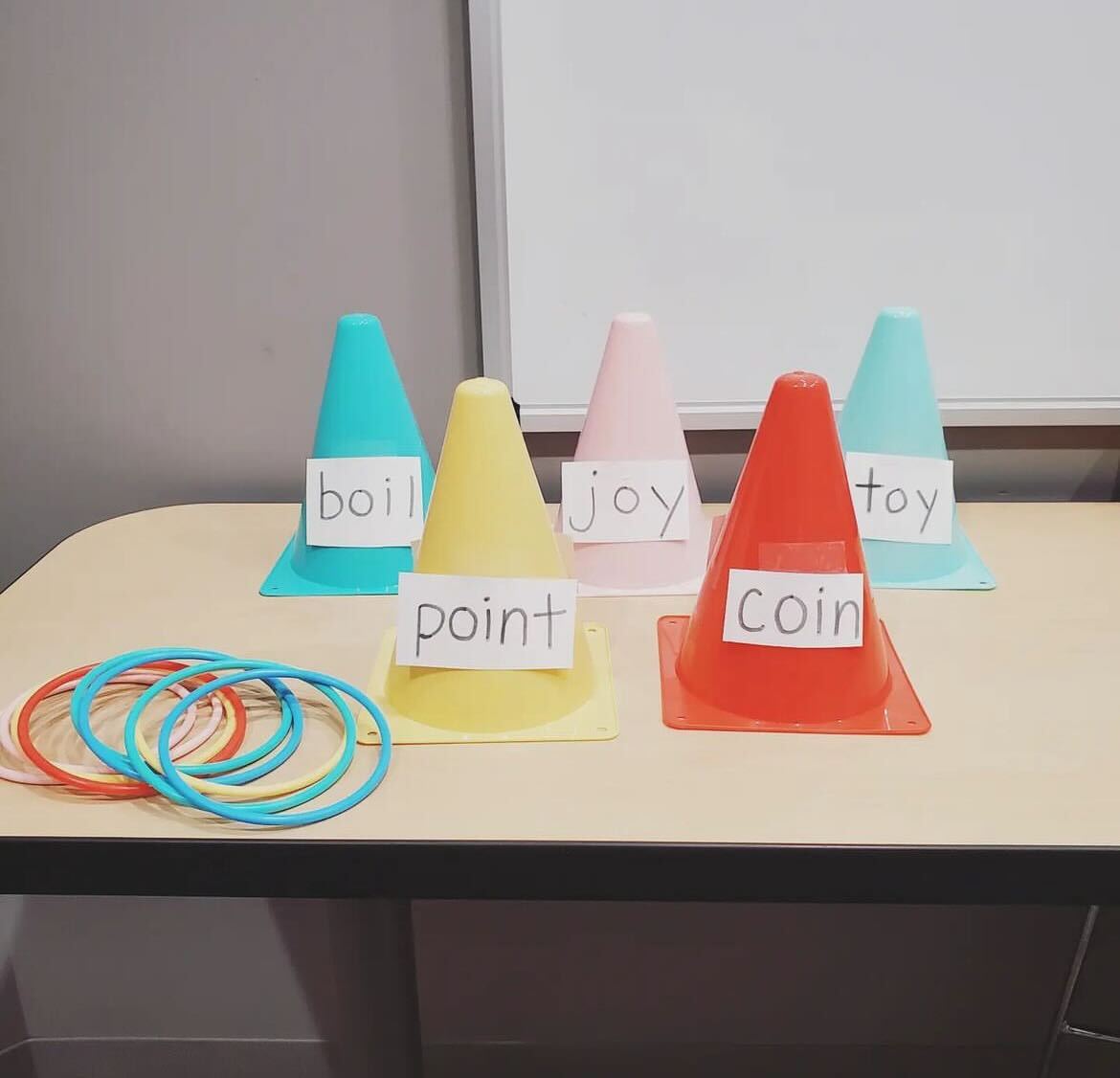 Cones and rings displayed on table. Cones have sight words velcroed to the front, from left to right: boil, point, joy, coin, toy.